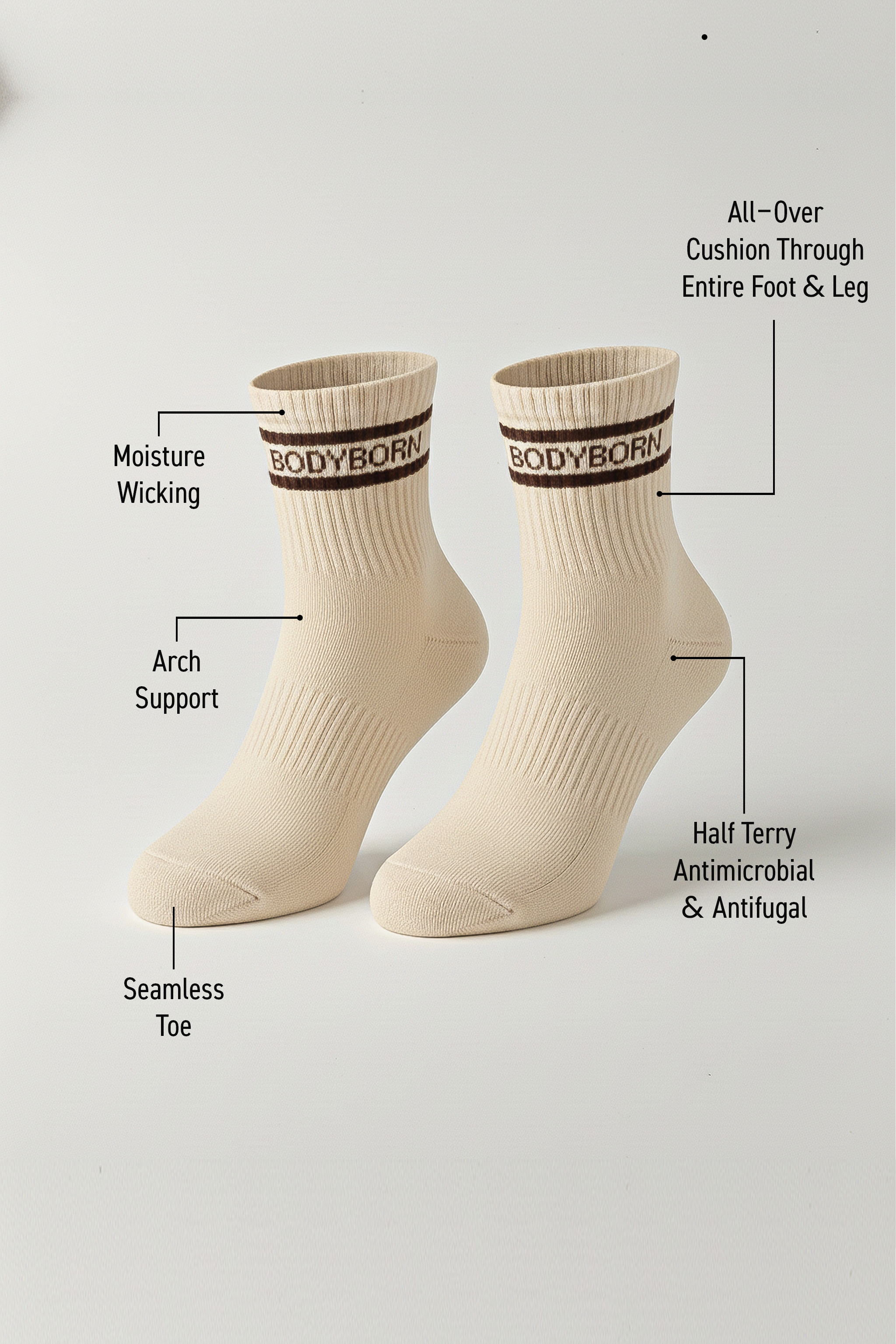 Two beige BODYBORN ankle-length socks with brown logo and stripe detail, displayed upright with labeled features including moisture-wicking material, arch support, antimicrobial and antifungal half-terry construction, all-over cushioning through the foot and leg, and seamless toe