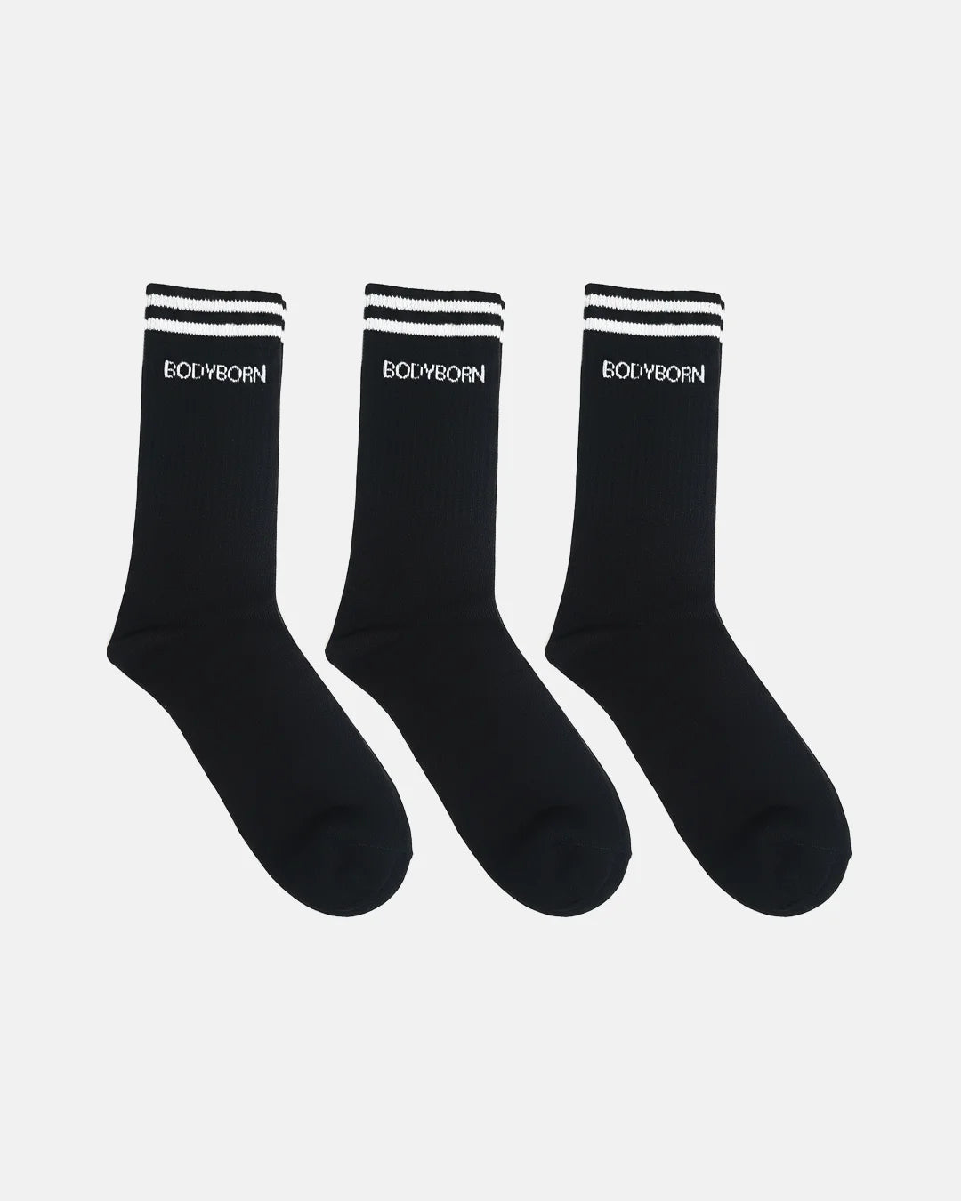 Three black crew-length socks displayed in a row on a white background, designed with ribbed texture, white double-stripe detail at the cuff and BODYBORN branding