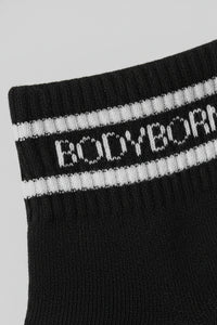 Black sock with white stripes and 'BODYBORN' branding on a light gray background with a premium feel, soft and comfortable