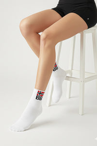 A person wearing white socks with a bodyborn logo, sitting on a white stool in ankle size
