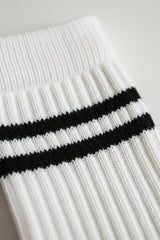 Close-up of a white sock with black stripes on a light gray background in crew size soft and comfortable