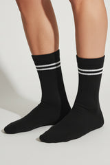 Black socks with white stripes worn by a person on a light gray background comfortable and soft 
