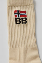 Beige sock with a knit bodyborn logo featuring a flag and text on a gray background in crew size premium soft and comfortable