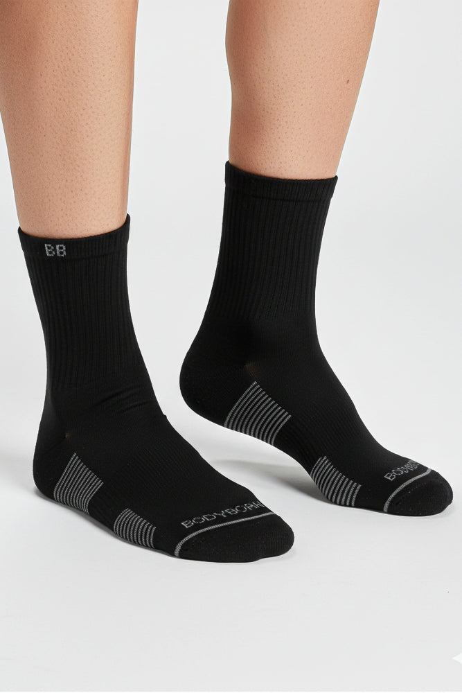 Black socks with bodyborn logo worn by a person on a light gray background in crew size soft and comfortable