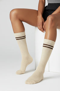 Person wearing beige knee-high socks with brown stripes on a light background premium feel, soft and comfortable