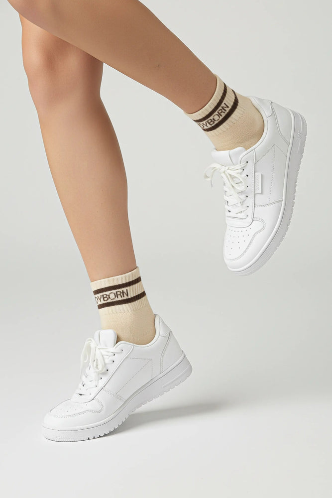 White sneakers and bodyborn beige socks with brown stripes on a light gray background premium feel, soft and comfortable