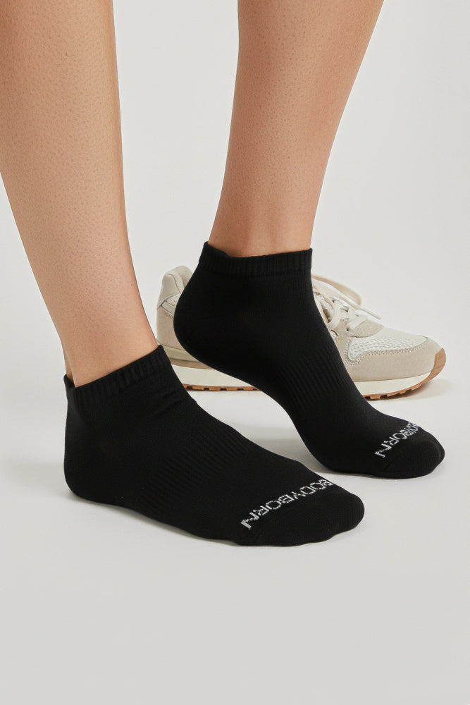 Black low cut socks worn with white sneakers on a light gray background comfortable and soft