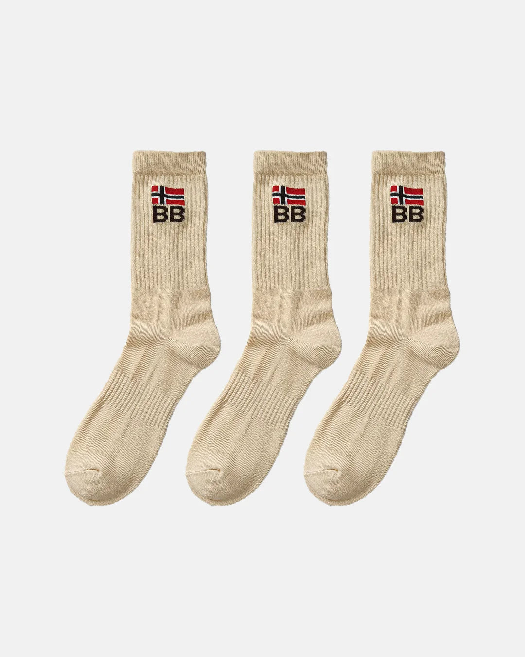 Three beige crew-length socks arranged in a row on a white background, each showing ribbed fabric and an embroidered BB logo beneath a red and white flag symbol