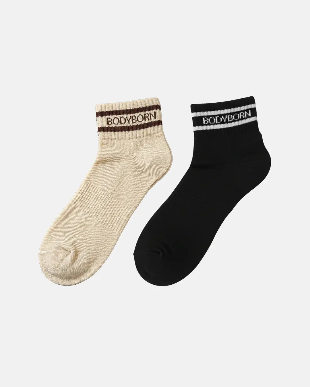 Two ankle-length BODYBORN socks shown side by side one beige with brown stripe detail and one black with white stripe detail both designed with ribbed texture and branded cuff